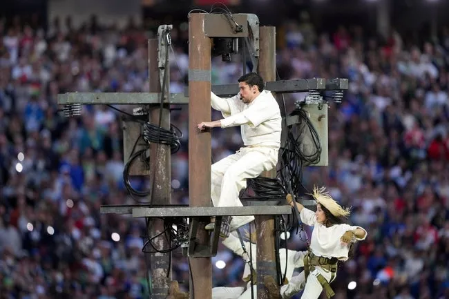 Feb 8, 2026; Santa Clara, CA, USA; Bad Bunny (center) climbs a utility pole while performing during halftime in Super Bowl LX between the New England Patriots and the Seattle Seahawks at Levi's Stadium. © Darren Yamashita-Imagn Images